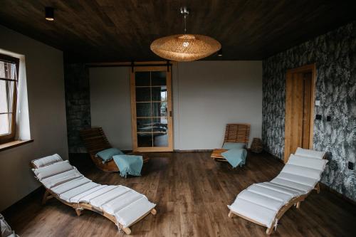 a living room with white chairs and a chandelier at eM Apartments Javorník in Vacov