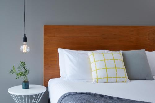 a bedroom with a bed with a wooden headboard at Cosmopolitan Hotel and Apartments in Melbourne