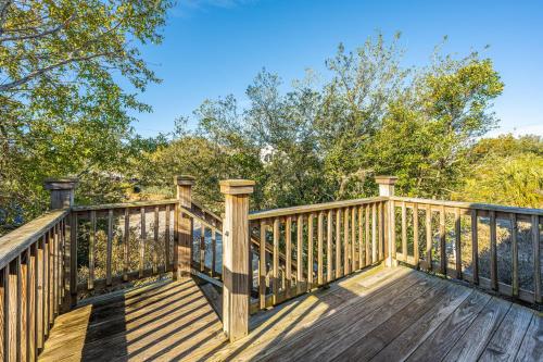 a wooden deck with trees in the background at Serenity Now in Edisto Island