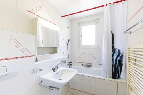 a white bathroom with a sink and a window at La Maison des Amis - A in Le Chatelard
