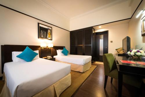 a hotel room with two beds and a desk at Hotel Sentral Johor Bahru @ Woodland Causeway in Johor Bahru