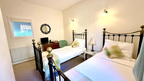 a bedroom with two beds and a mirror at The Bull Inn in Little Walsingham