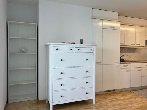 Una cocina con gabinetes blancos y una cómoda blanca. en Studio avec accès direct au lac de Geneve, en Saint-Gingolph