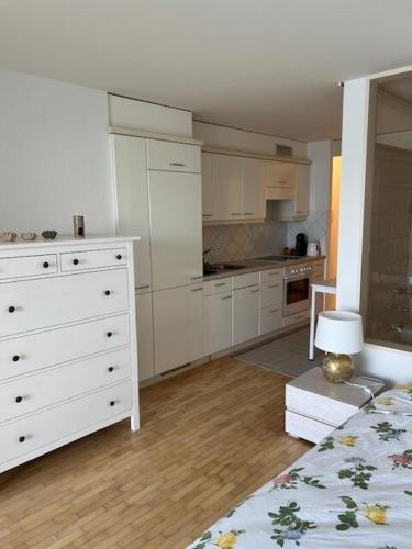 a kitchen with white cabinets and a white dresser at Studio avec accès direct au lac de Geneve in Saint-Gingolph