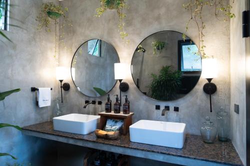 two sinks in a bathroom with two mirrors at The Getaway Bailen in General Emilio Aguinaldo