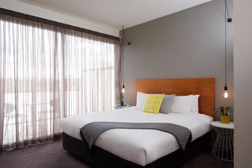 a bedroom with a large bed and a large window at Cosmopolitan Hotel Melbourne in Melbourne