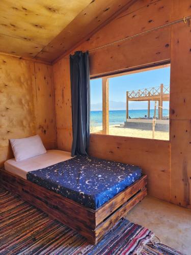 a bed in a wooden room with a view of the beach at Southern spirit in Nuweiba
