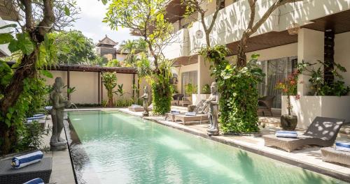 ein Swimmingpool vor einem Haus mit Bäumen in der Unterkunft Swiss-Belcourt Sunset in Seminyak
