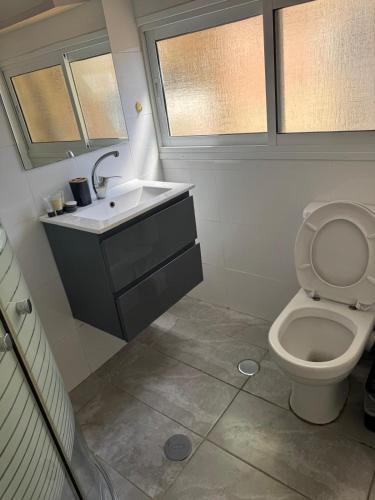 a bathroom with a toilet and a sink and two windows at מגדלי חי 3 in Eilat