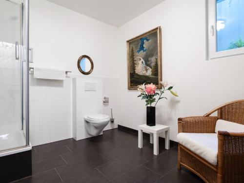 a bathroom with a toilet and a chair and a vase of flowers at Beim Thöny - schönes Apartment mit privatem Zugang in Utting am Ammersee