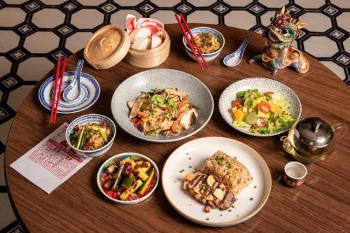 a wooden table with plates of food on it at The Character China Town เดอะ คาแรคเตอร์ เยาวราช Mrt วัดมังกร in Khlong San