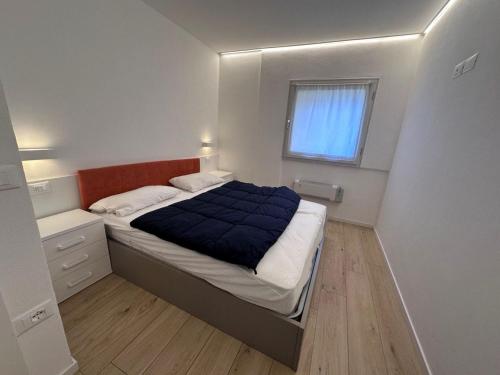 Un dormitorio pequeño con una cama y una ventana. en White Apartment, en Peio Fonti
