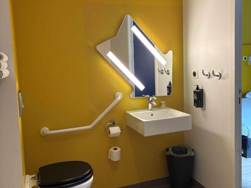 a bathroom with a toilet and a sink and a mirror at ibis budget Rennes Rte Lorient in Rennes