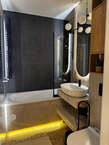 a bathroom with a sink and a toilet and a tub at Family & Business Apartments PREMIUM No 2 - 1 Bedroom with Private Jacuzzi, Balcony, Parking in Warsaw