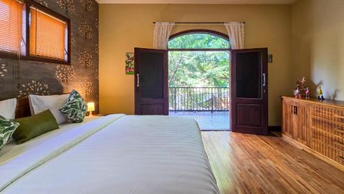 a bedroom with a large bed and a large window at Dalai Tropical in Kuta Lombok