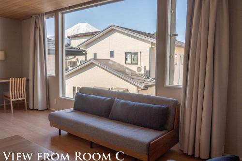 a living room with a couch and a large window at Ginkgo House ギンコハウス in Fujiyoshida
