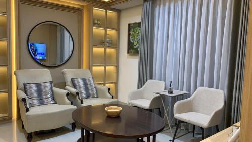 PondokpucungにあるApt Embarcadero 2BR with Wi-Fi & Pool ByDamaresaのリビングルーム(椅子、テーブル、鏡付)