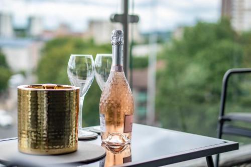 a bottle of wine sitting on a table with two glasses at Luxury 2BR Penthouse-1, Private Terrace, City Center, Free Parking in Leeds