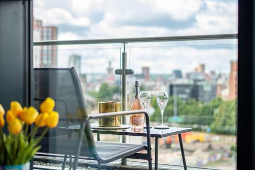 une table avec des verres et une bouteille de vin sur une fenêtre dans l'établissement Luxury 2BR Penthouse-1, Private Terrace, City Center, Free Parking, à Leeds