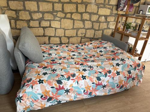 a bed with a flowery comforter on it at Beau Studio in Gouvieux