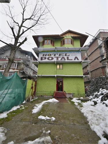 a green building with a sign on top of it at Potala Hotel in Jāmb