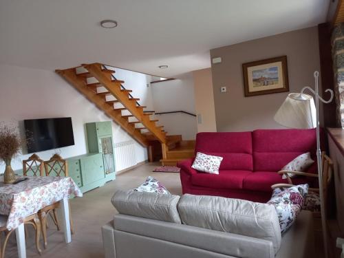 a living room with a red couch and a staircase at Casa El Rincón in Santa Eulalia de las Manzanas