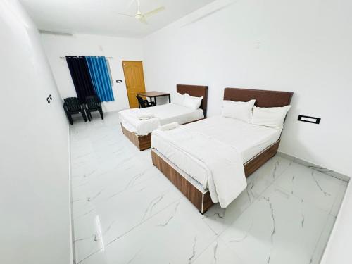 um quarto branco com 2 camas e um espelho em eden homestay em Munnar