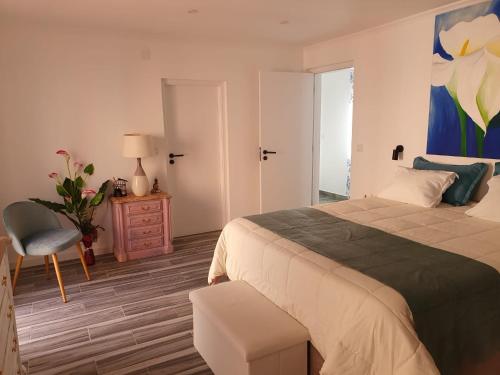 a bedroom with a large bed and a chair at Casa do Arelho in Óbidos