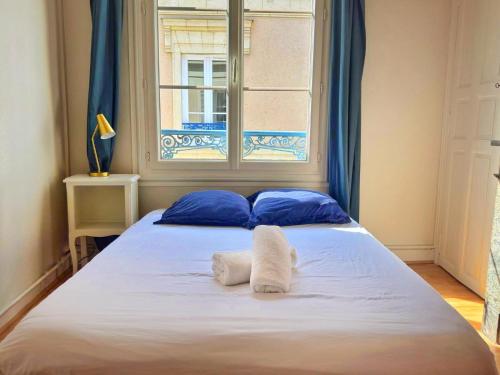 een slaapkamer met een bed met blauwe kussens en een raam bij Le Marceau in Angers