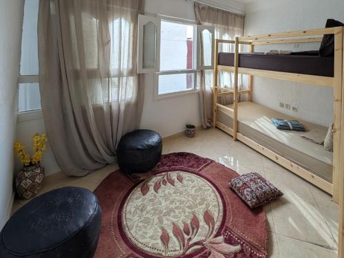 a room with two bunk beds and a rug at Tayyurt Blue waves Beach house's in Oulad Akkou