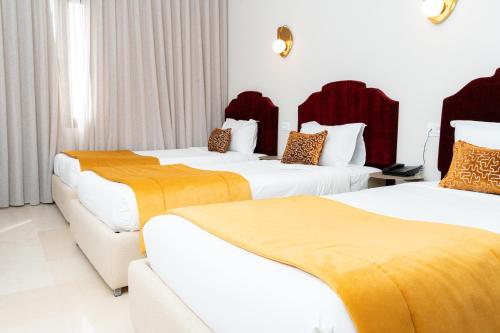 two beds in a hotel room with yellow and white at hôtel LE PACHA in Tunis