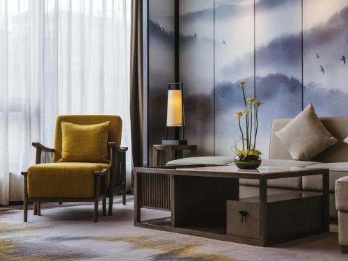 a living room with a yellow chair and a table and a couch at Pullman Fuzhou Tahoe in Fuzhou