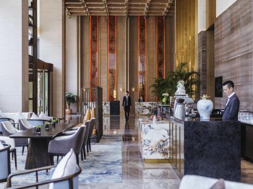 a man in a suit walking through a restaurant at Pullman Fuzhou Tahoe in Fuzhou