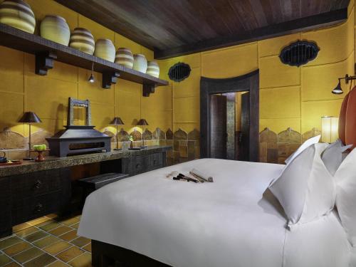 a bedroom with a large white bed and a stove at Legacy Yen Tu - MGallery in Uông Bí