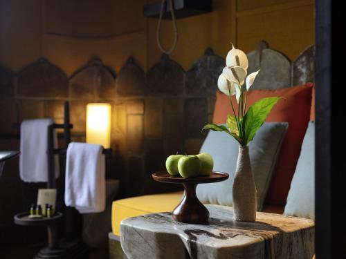 a table with a vase with a flower and apples on it at Legacy Yen Tu - MGallery in Uông Bí