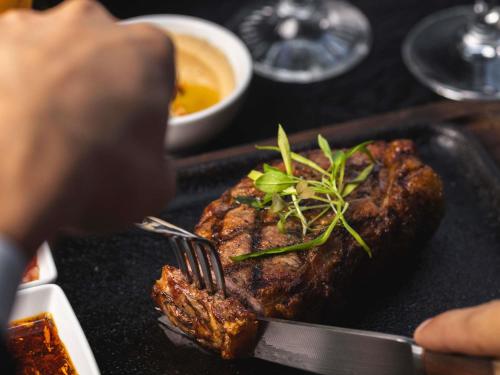a person eating a steak on a plate with a fork at Palladio Hotel Buenos Aires - MGallery Collection in Buenos Aires