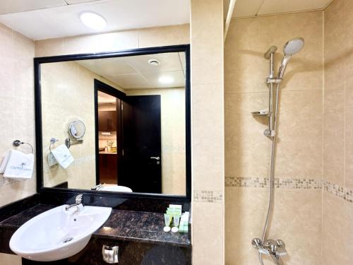 a bathroom with a sink and a shower with a mirror at Cosmos Living Delightful Studio with Balcony in Dubai