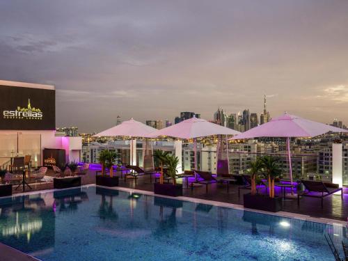 a pool on the roof of a building with umbrellas at The Canvas Dubai - MGallery Hotel Collection in Dubai