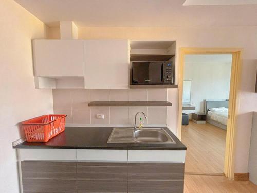 Una pequeña cocina con fregadero y microondas. en 芭提雅市中心大空间公寓酒店预定 城景健身房泳池舒适型公寓 日租周租月租灵活, en Pattaya South