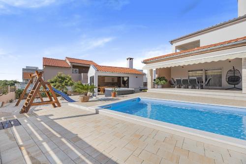 a backyard with a swimming pool and a house at Villa Kunfin ZadarVillas in Bibinje