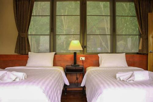 two beds in a room with two windows at Bhumisiri Hill Khaoyai in Ban Tha Chang