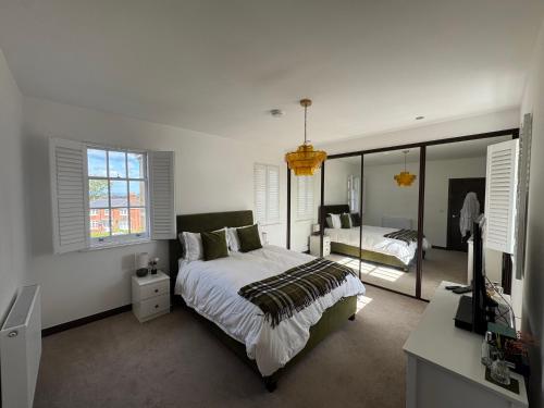Un dormitorio blanco con una cama y un espejo. en Leishman Views, en Itchen Abbas