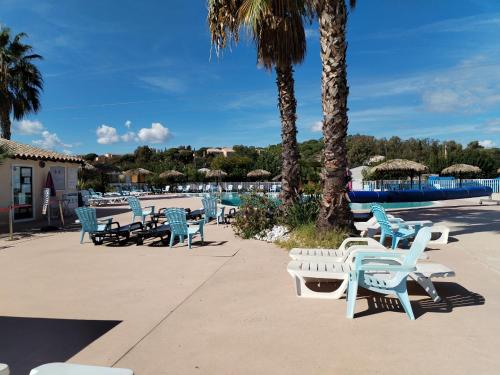 a group of chairs and tables and palm trees at Le SPLENDIDE in Fréjus