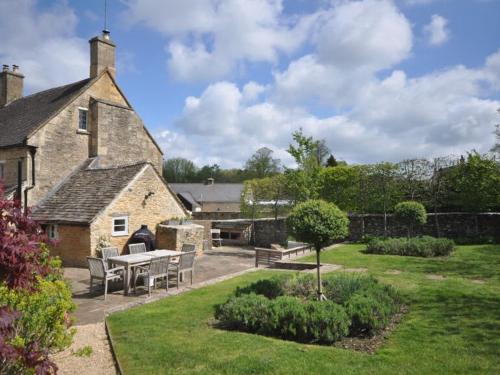 a house with a table and chairs in a yard at Jasmine Cottage, Upper Slaughter, Cotswolds in Cheltenham