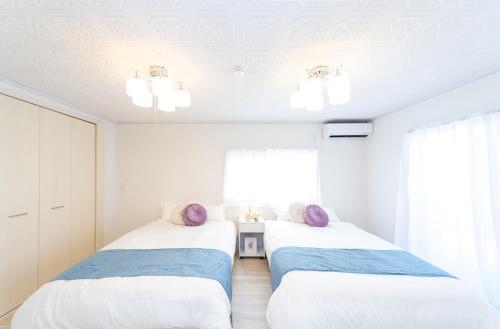 two beds in a white room with a window at Miraie Yatomi Large house in Yatomi