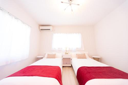 two beds in a room with white walls and a window at Miraie Yatomi Large house in Yatomi