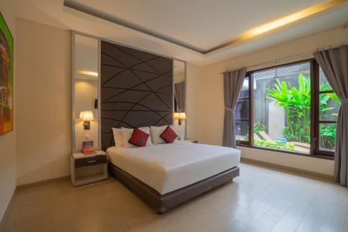 a bedroom with a bed and a large window at Swiss-Belvillas Umalas in Canggu