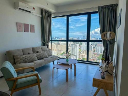 a living room with a couch and a large window at Cozy Urban Suites Georgetown View in Jelutong