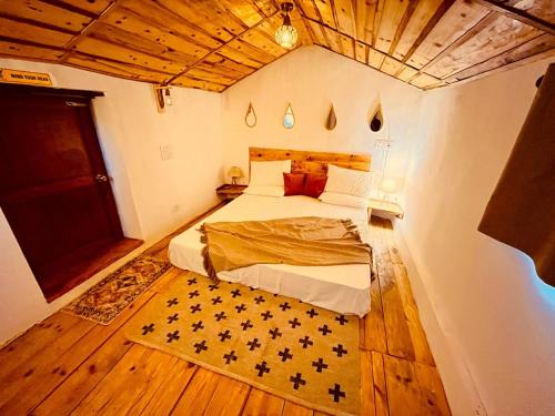 a bedroom with a bed and a wooden ceiling at Arameh-A Boutique Orchard Retreat Near Kasauli in Rājgarh