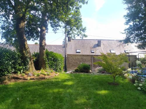Un patio con árboles y una casa con césped verde. en Gîte Youna - Nature et charme breton entre Lizio et Josselin, en Lizio
